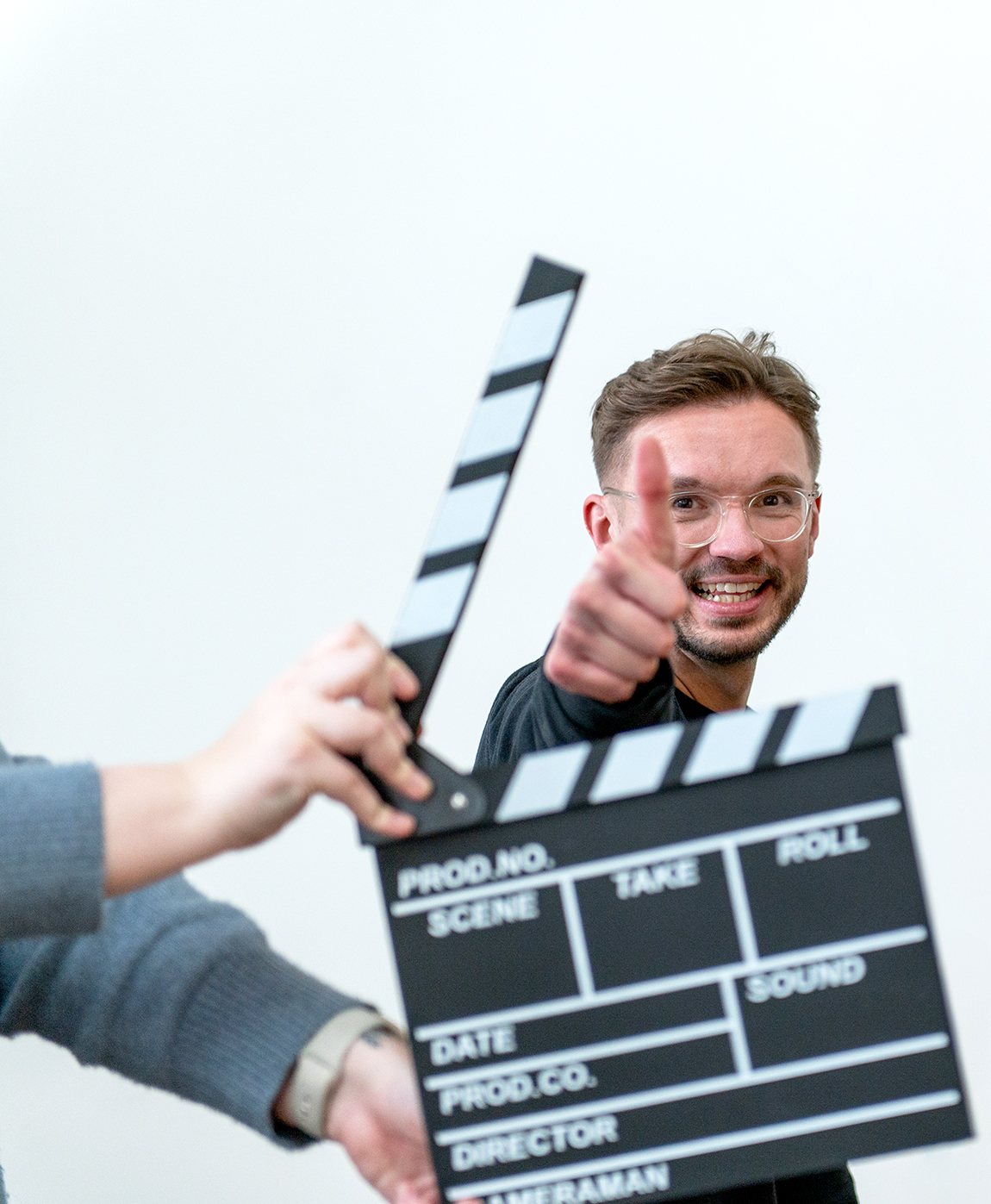 Rob Curtis giving a thumbs up behind a film clapperboard